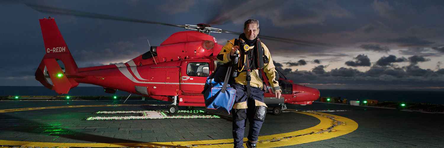 QMU graduate Norman Todd standing in front of a helicopter