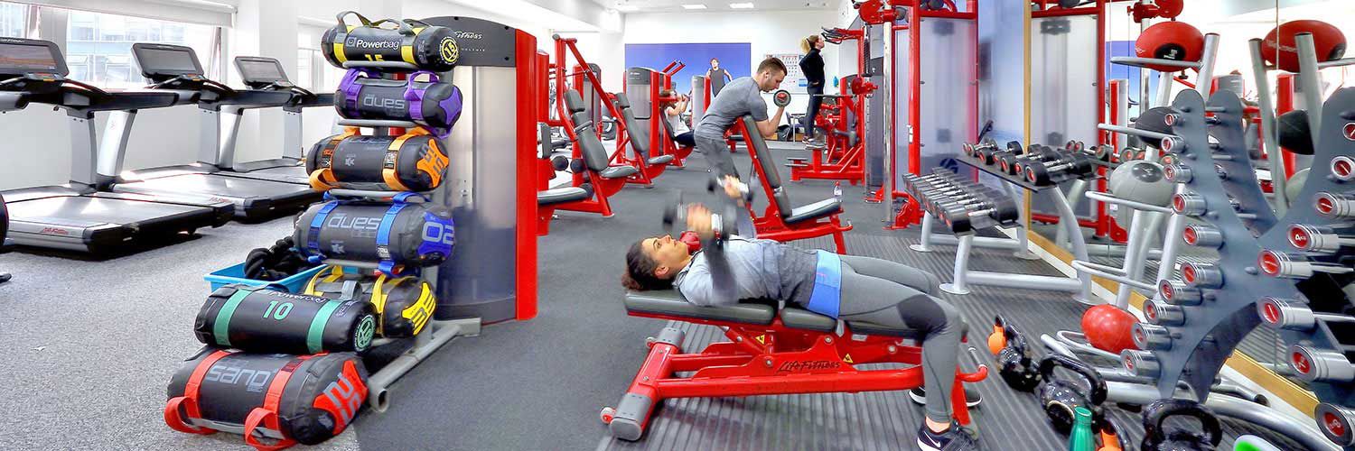 A quiet, well equipped gym with a handful of people working out at different stations