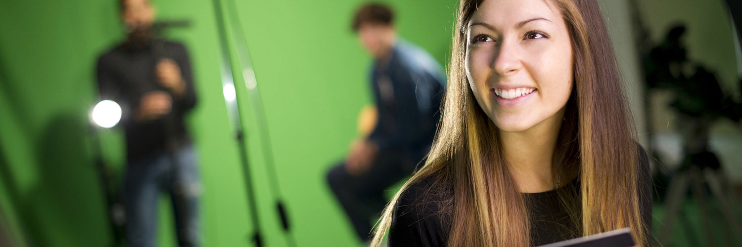 Female in front of a green screen with cameras