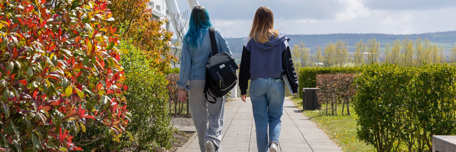 Two people walking together on the QMU campus