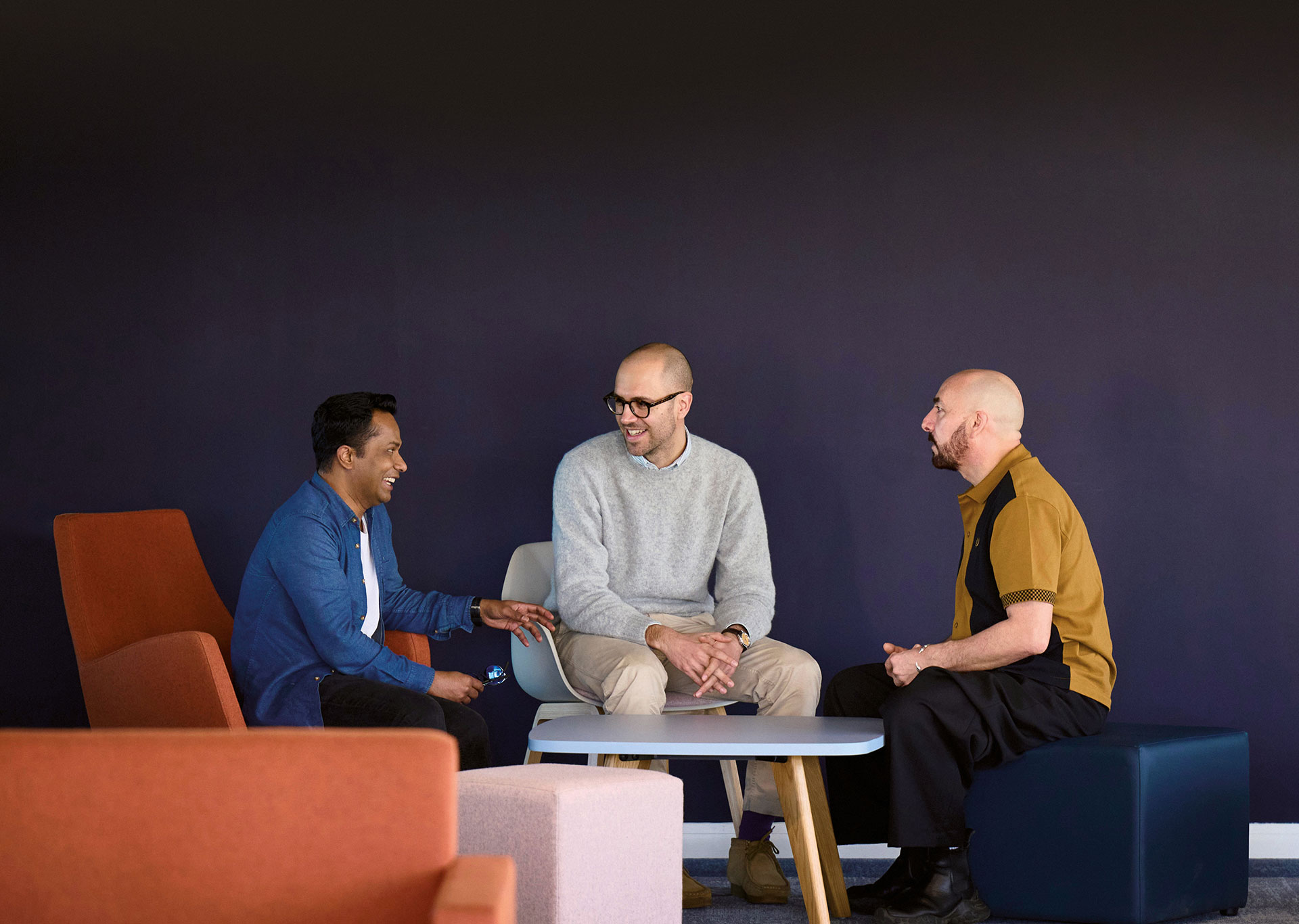 Photo of three men talking in modern room with purple walls