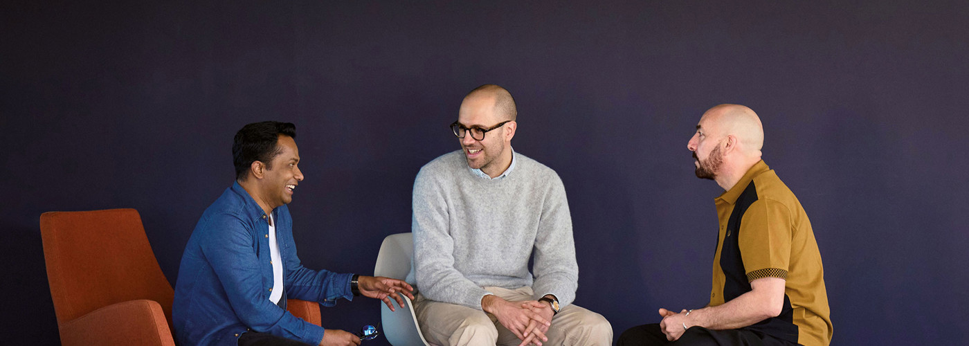 Photo of three men talking in modern room with purple walls