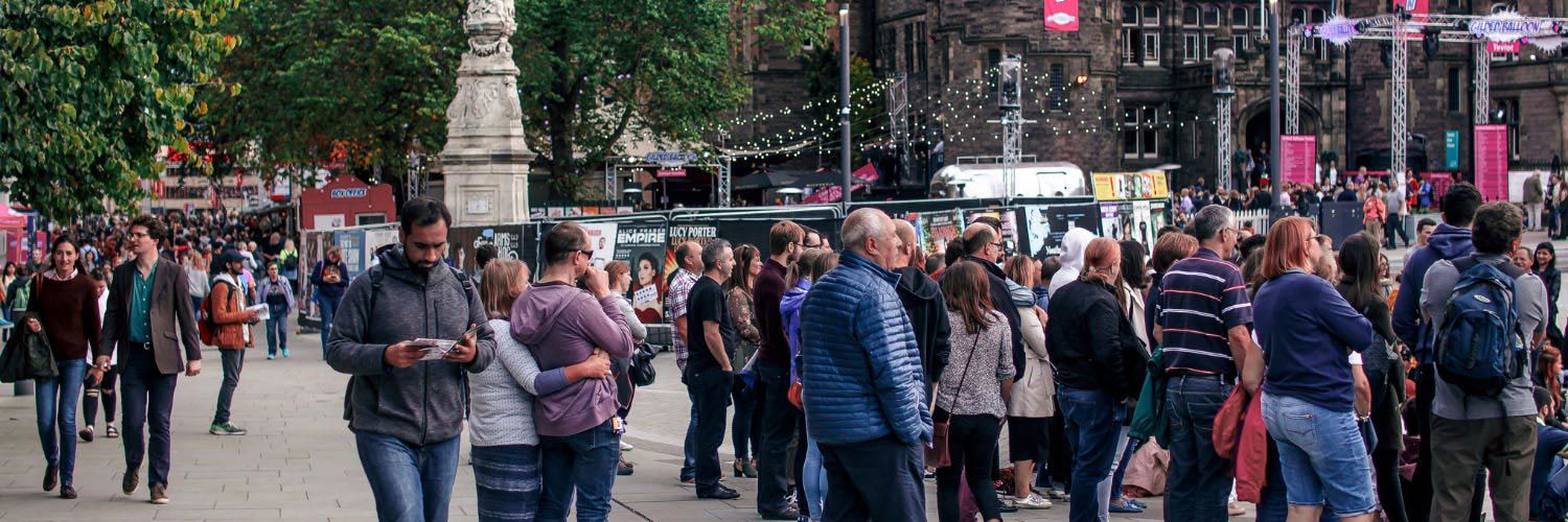 A panoramic shot of Edinburgh Fringe Festival with people walking along the street.