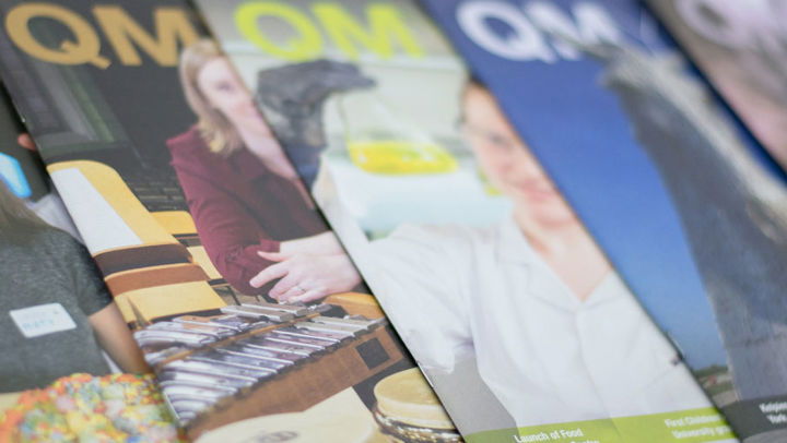 Several different issues of the QMYou magazine stacked on each other