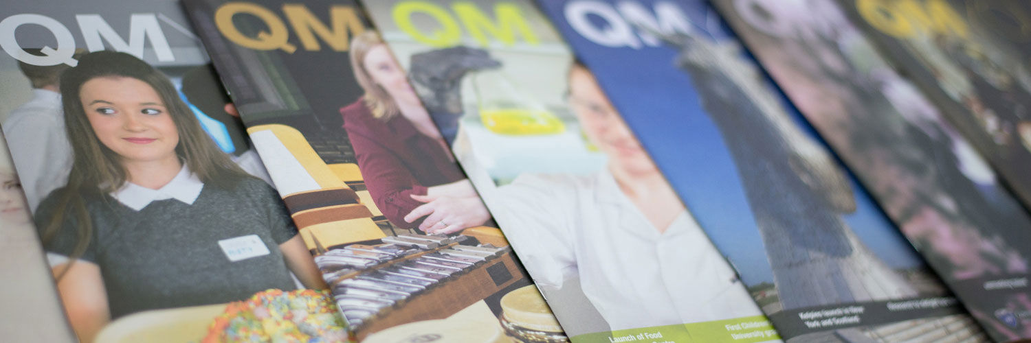 Several different issues of the QMYou magazine stacked on each other