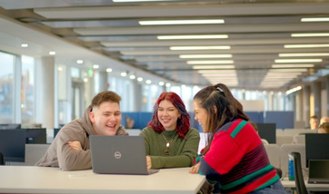 Three students laughing and looking at a laptop in QMU's Learning Resource Centre