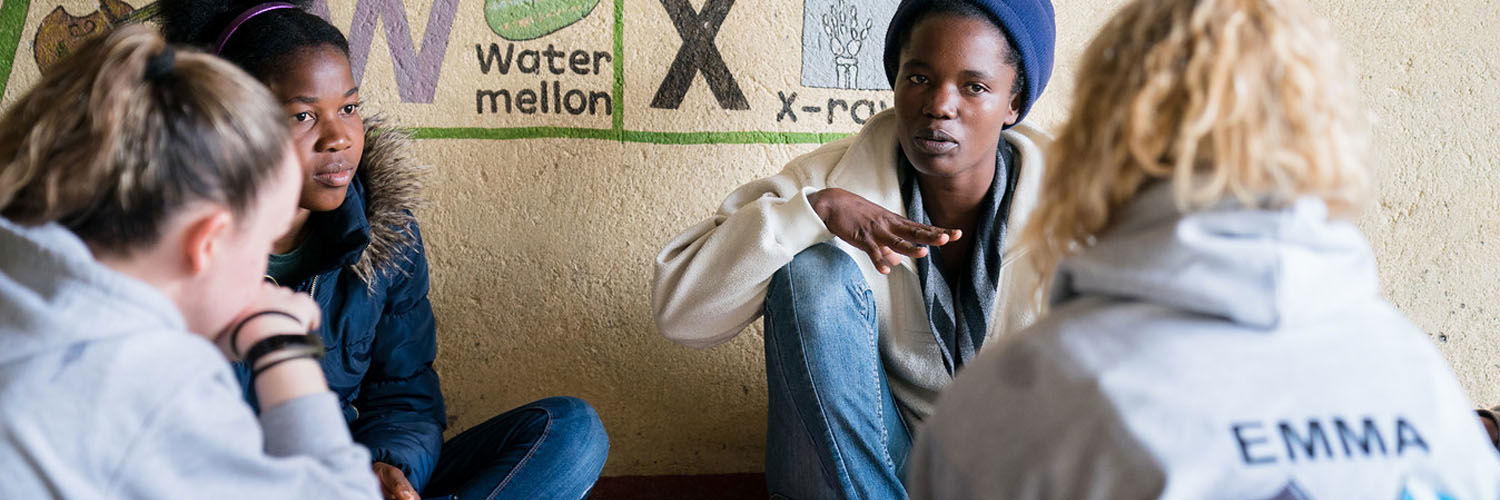 A group of young people engaged in dialogue in a classroom setting.