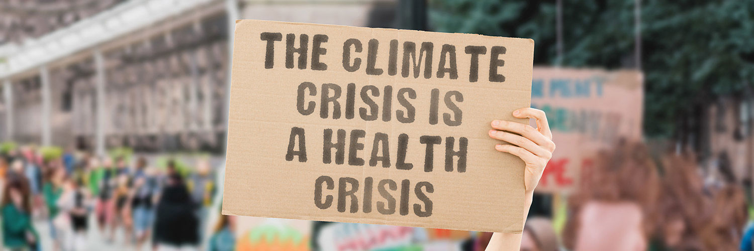 Photo of someone holding up placard that reads - The climate crisis is a health crisis