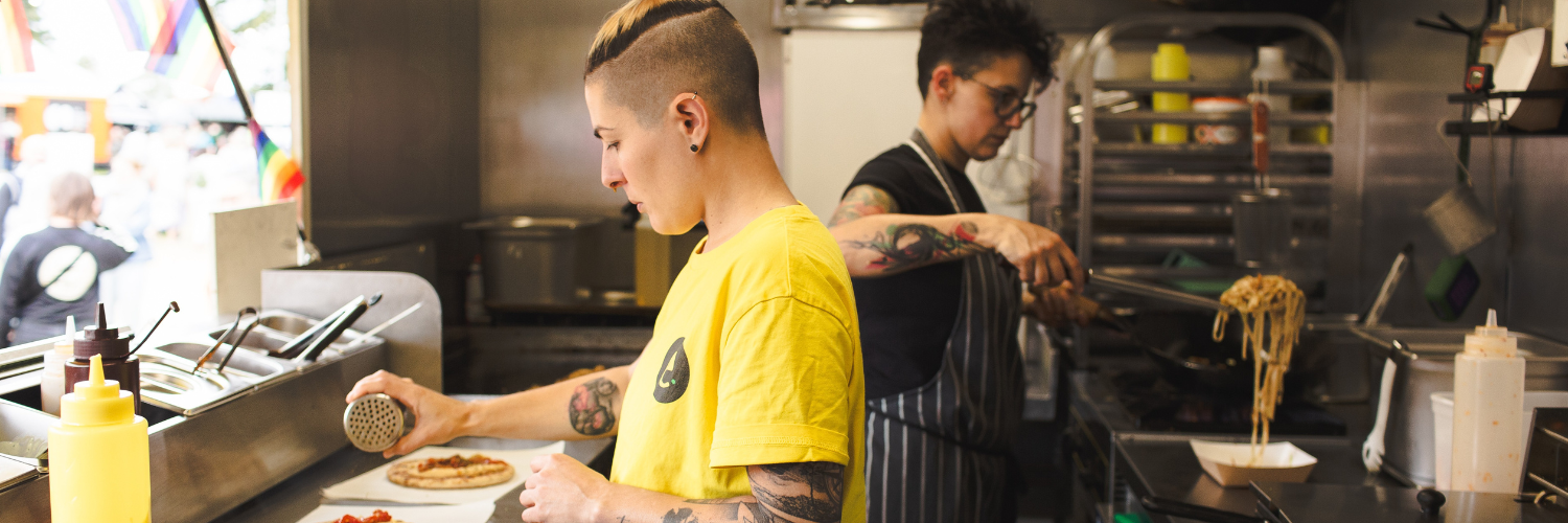 Two people in a food truck cooking. 