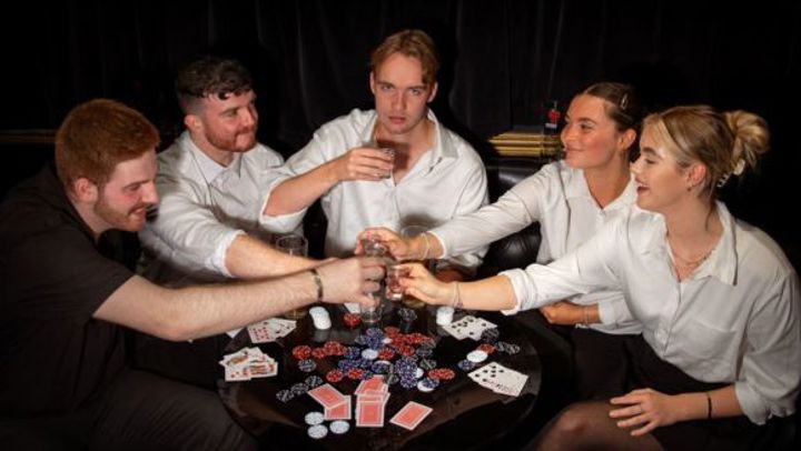 A group of 5 young people playing poker