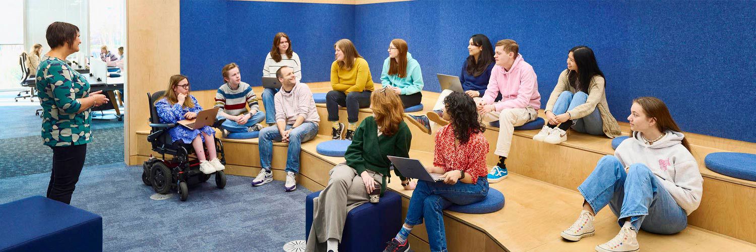 A teacher speaks to a group of students sitting on the stepped seating in one of the library teaching spaces.