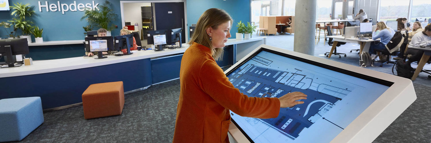 A young woman using a large, free-standing touch screen device.