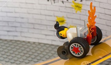 Lego character in a modern wheelchair with stars on the wheels and flames the exterior