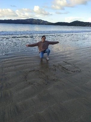 Image of Paula writing QMU on beach sand