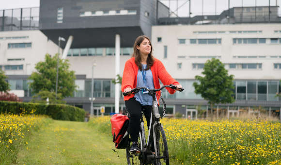 Student cycling on campus grounds