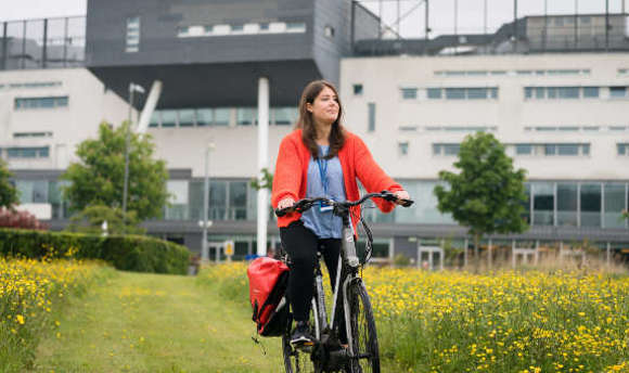 Student cycling on campus grounds