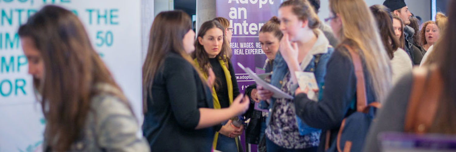 Several people engaged with various stalls at a student recruitment event