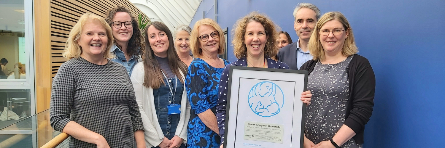 Group of nursing staff gathered together holding a framed certificate for the Baby Friendly Initiative.