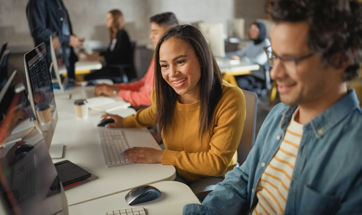 Several students working alongside one another in a library setting.