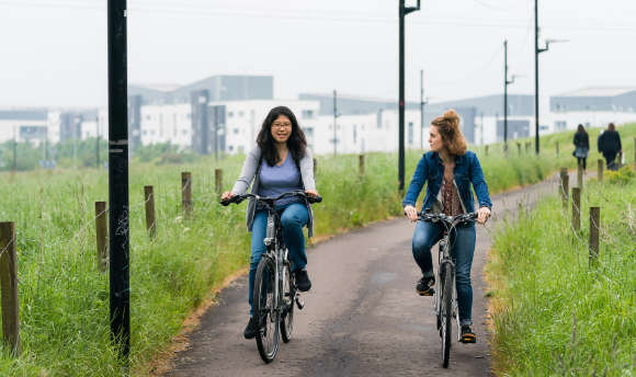 Friends cycling along a path between green fields