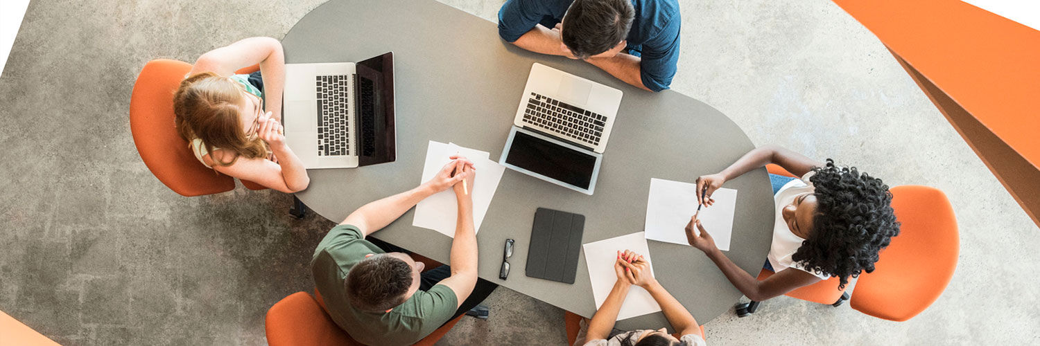 A group of people sat at a table, working on a project together. The photo is taken from directly above the table.