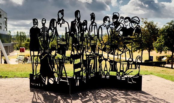 A steel sculpture of linocut-style cutouts of different individuals.
