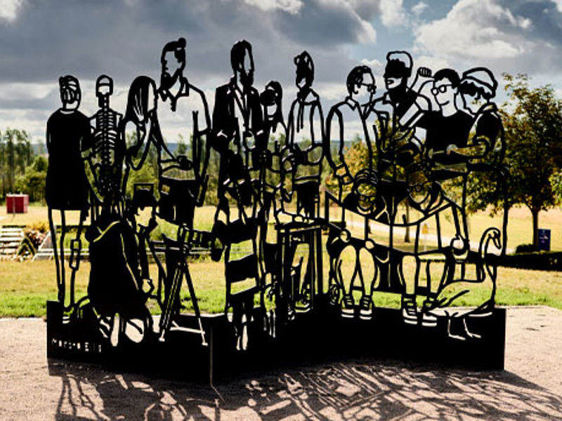 A steel sculpture of linocut-style cutouts of different individuals.