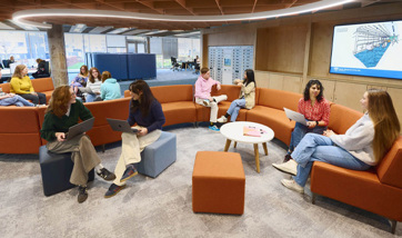 Several students sitting on the curved sofas within the library.