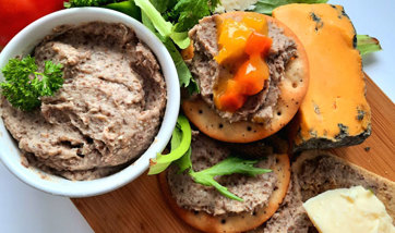 Parched pea pate on crackers with cheese, tomatoes and green leaves