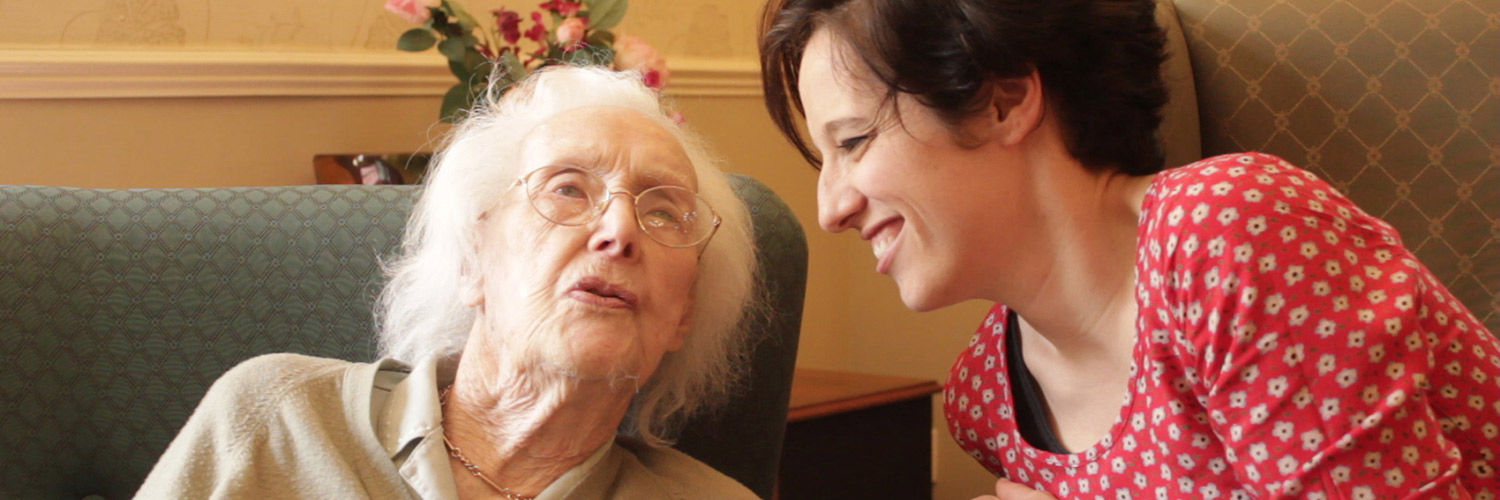 A young woman chatting with an elderly woman in a care home