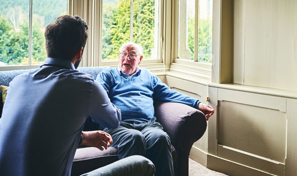 Elderly man in care home talking to staff
