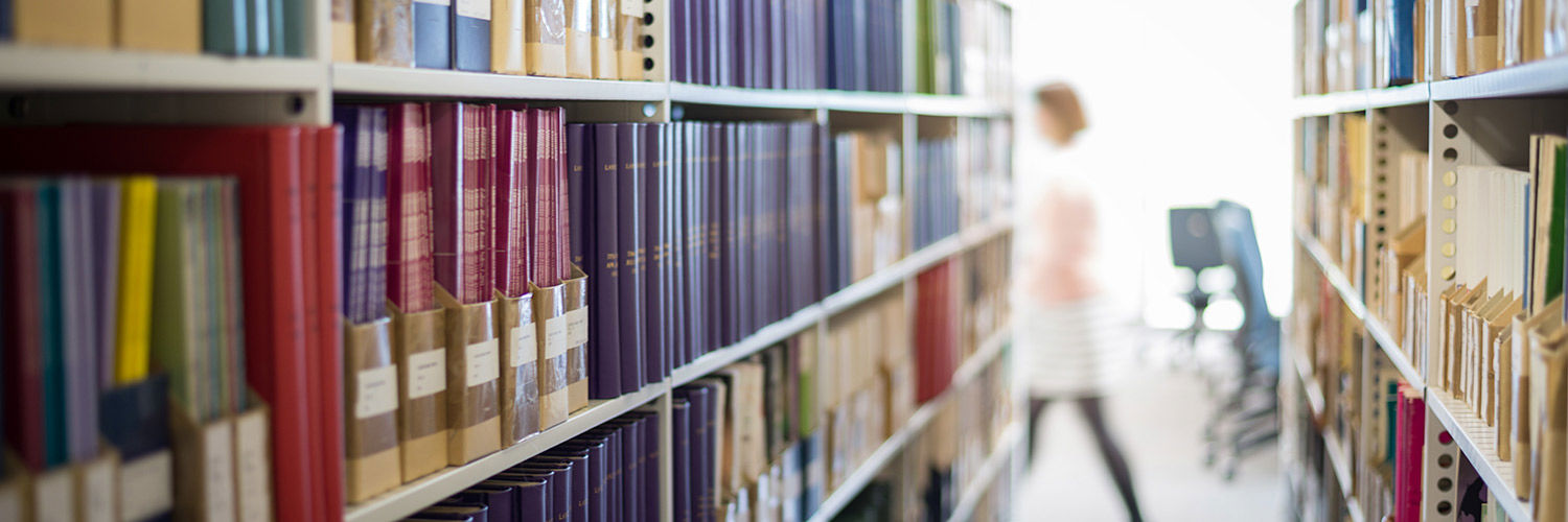 A close up shot of a bookshelf in the library filled with assorted reference material.