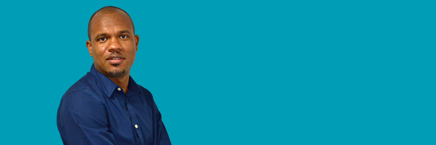 Head and shoulders shot of a Black man wearing a blue shirt and facing the camera.