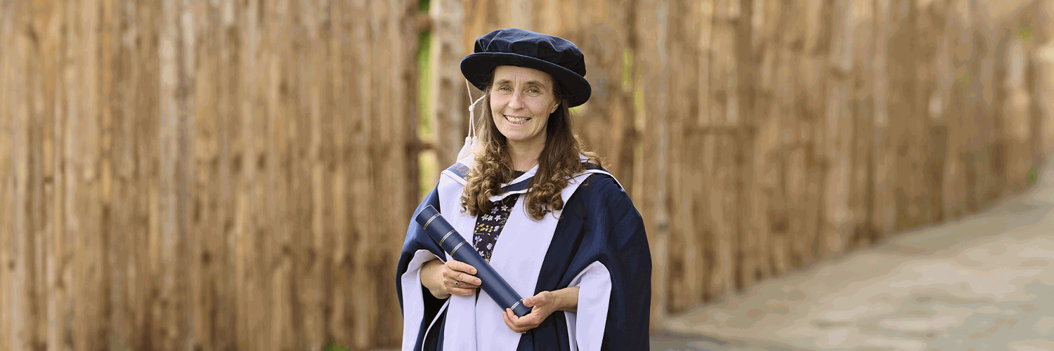 Juliet Robertson In Her Graduation Gown and Hat In Front Of QMU's Wee Forest