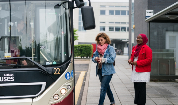 Two female students boarding a Lothian bus at the QMU campus bus stop 