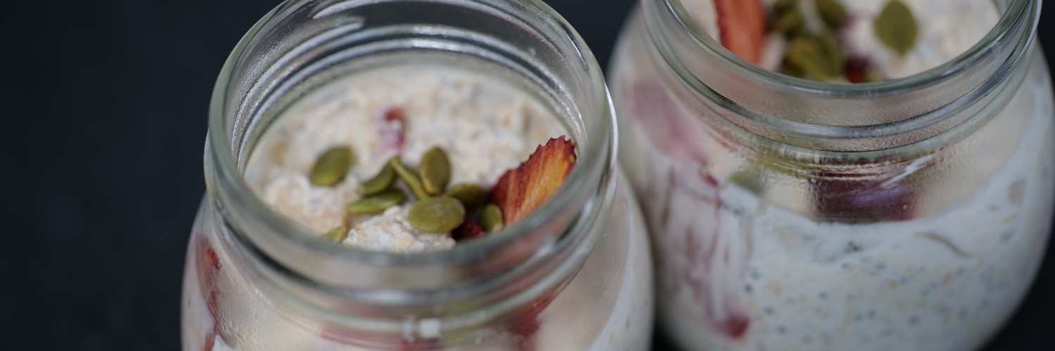 Two pots of overnight oats with pumpkin seeds and freeze dried strawberries