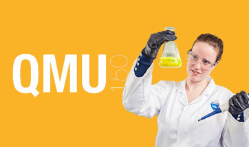 A scientist holding aloft a flask filled with a bright yellow liquid