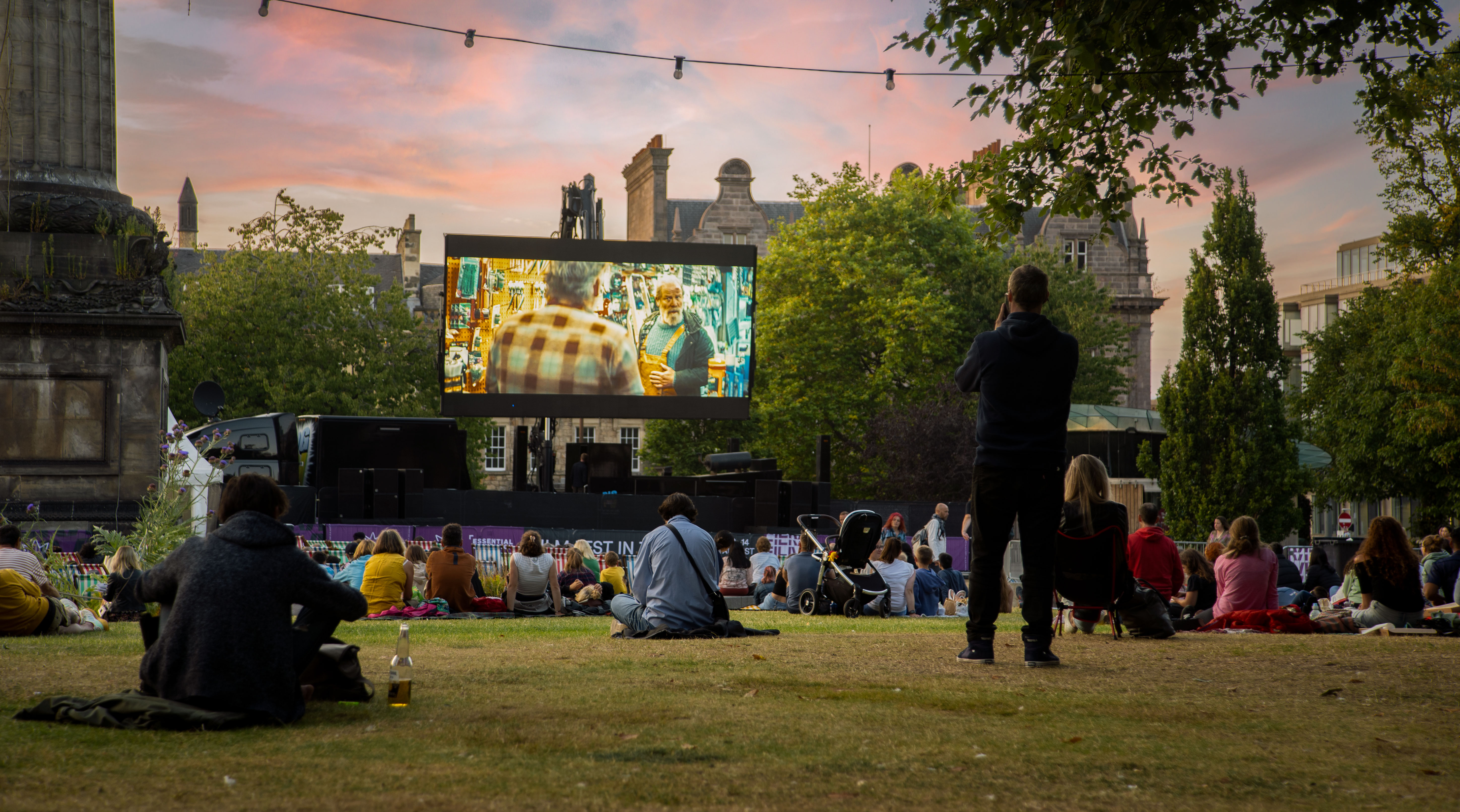 large film screen in front of an audience in public park