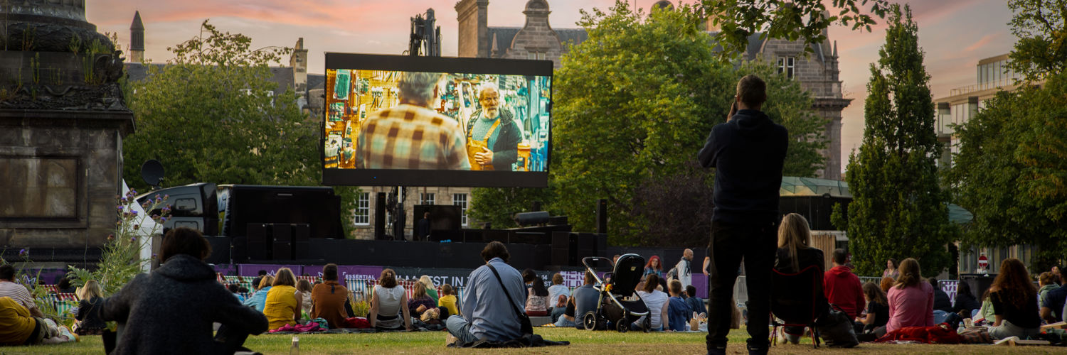 large film screen in front of an audience in public park