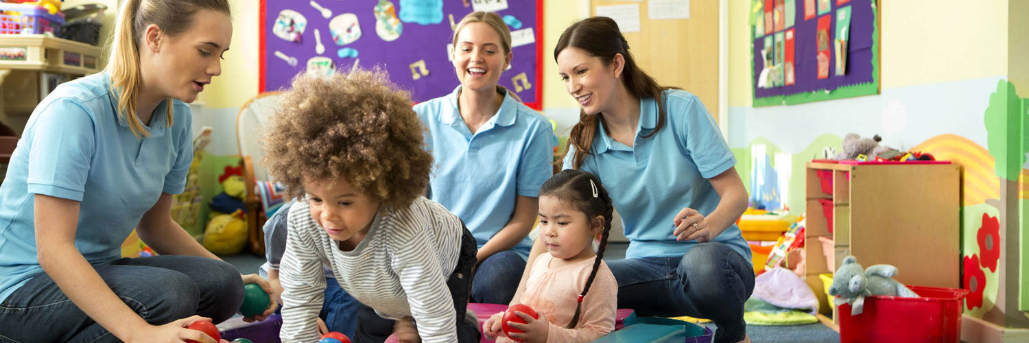 Three nursery staff playing games with two small children.