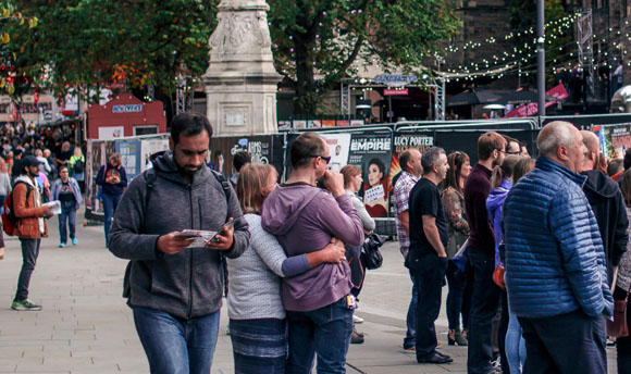 A panoramic shot of Edinburgh Fringe Festival with people walking along the street.