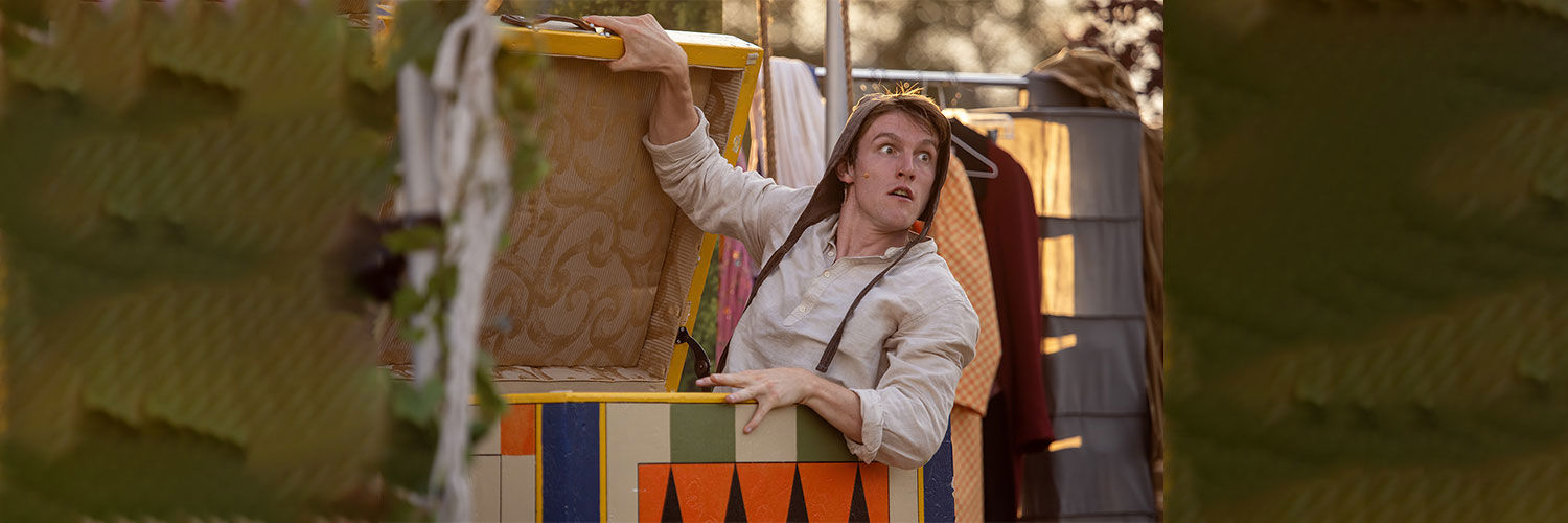 Matthew Mooney in theatrical costume ready to spring out of a box during an outdoor theatre performance