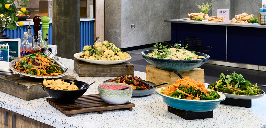 A salad bar featuring a range of dishes, including couscous, vegetables, pasta salad, salad greens, and sauces and dips.