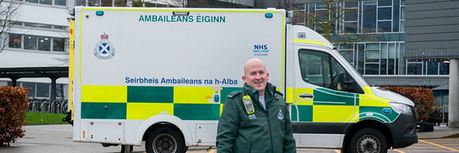 Paramedic smiling in front of ambulance