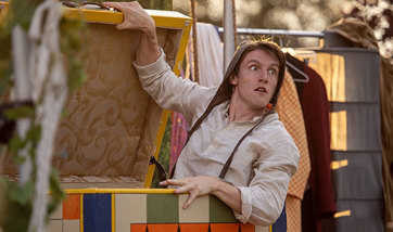 Matthew Mooney in theatrical costume ready to spring out of a box during an outdoor theatre performance
