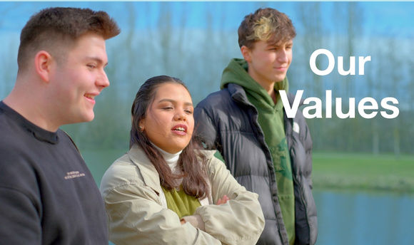 Three students standing around the pond at the QMU campus