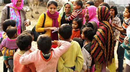 A couple of aid workers surrounded by a group of children