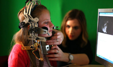 A child with a large piece of speech & language therapy equipment attached to their head