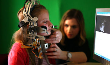 A child with a large piece of speech & language therapy equipment attached to their head