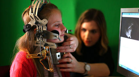 A child with a large piece of speech & language therapy equipment attached to their head